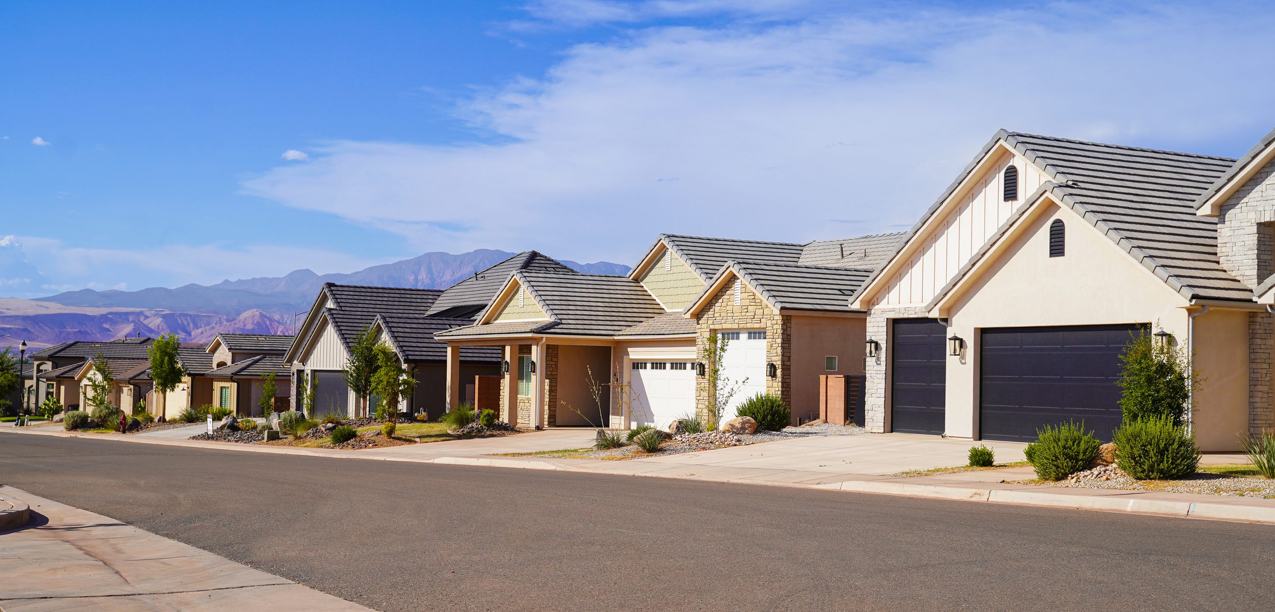 Suburban street with modern houses and mountains.
